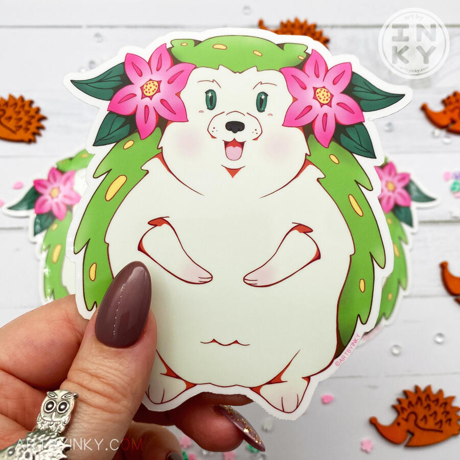 A person holding a grassy green hedgehog sticker.