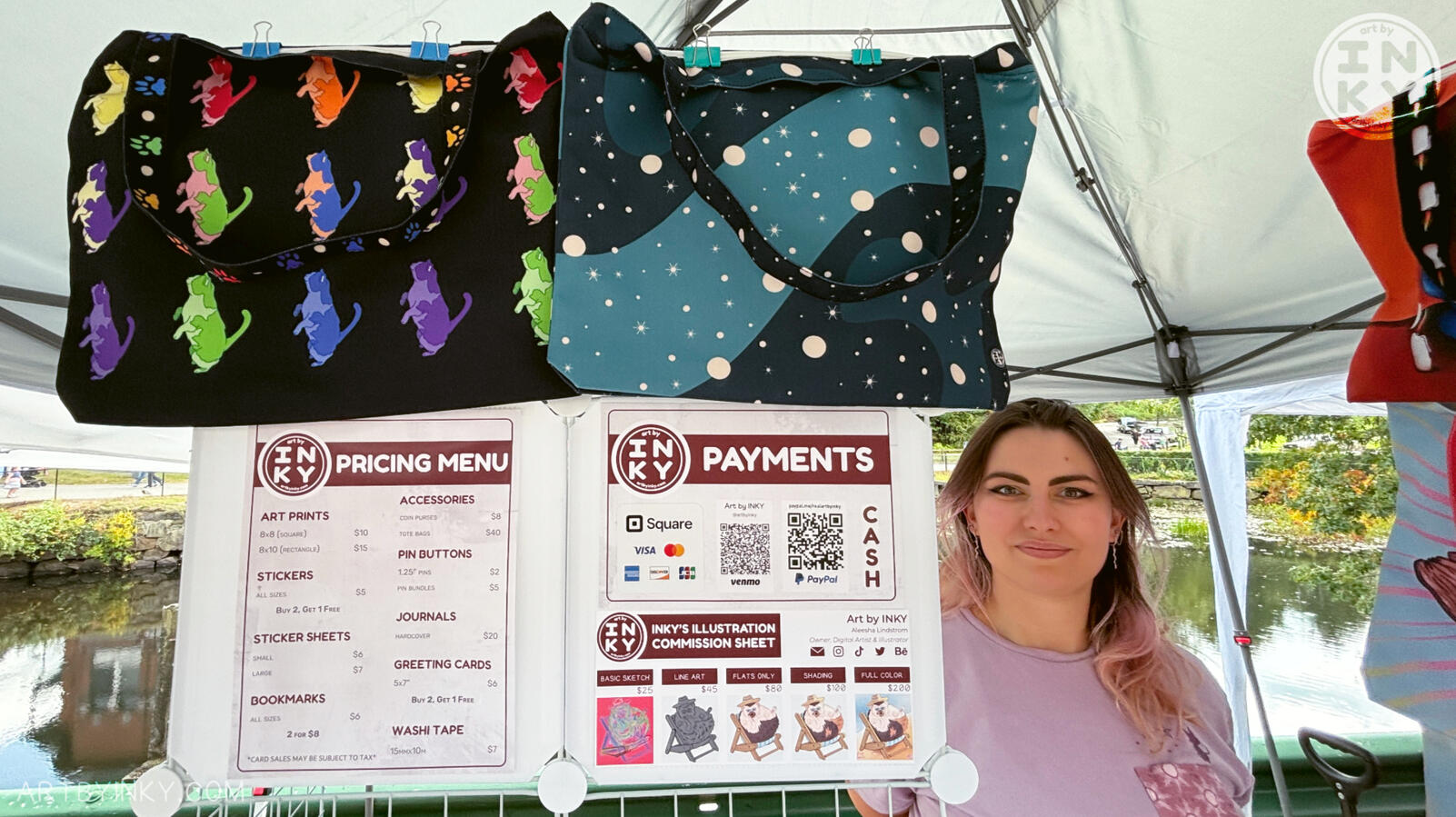 Front view of the booth layout at an outdoor market showing tote bags and sign displays.