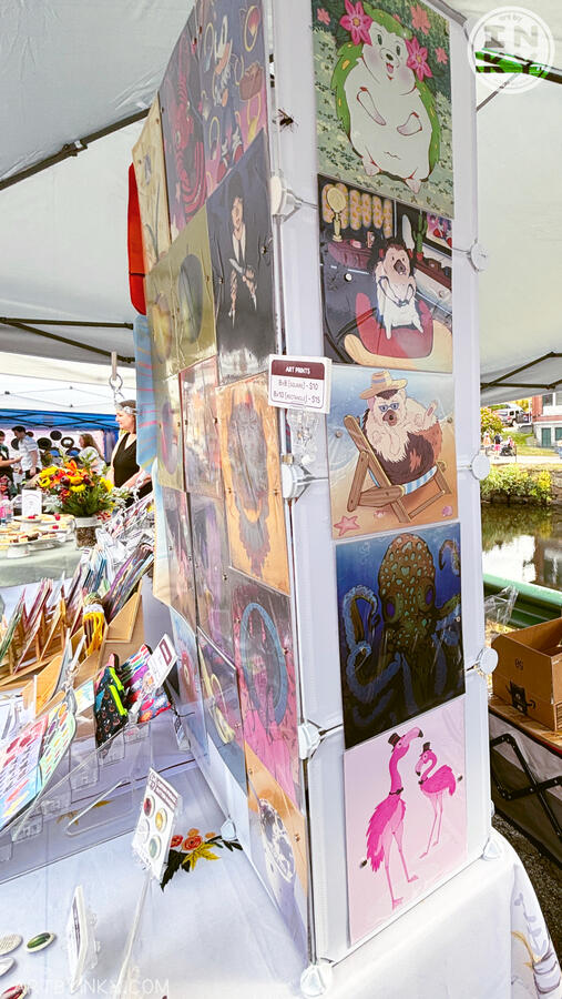 Side view of the booth layout at an outdoor market showing art prints and other goods.