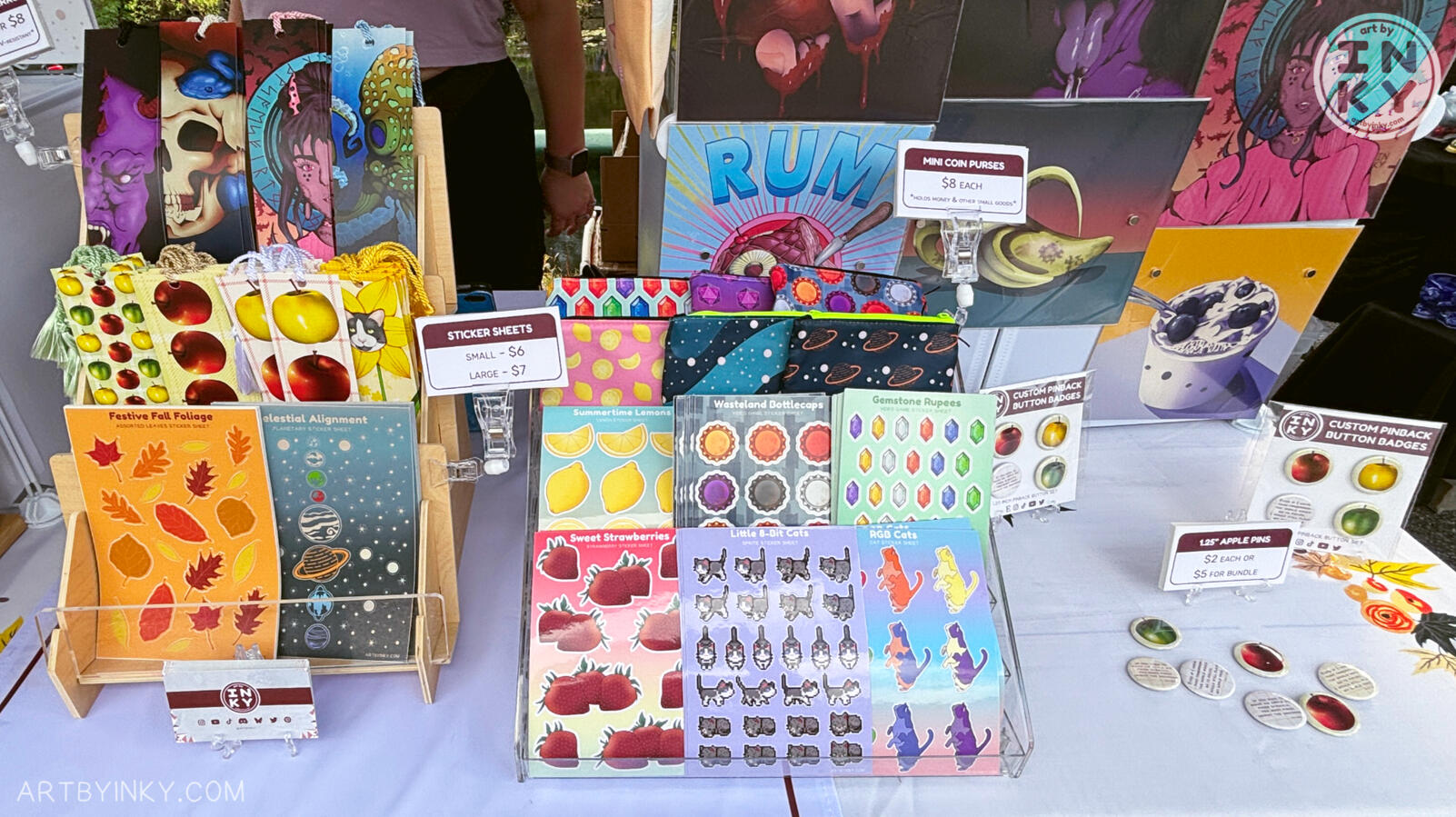 Outside Booth Front Right Side Front view of the booth layout at an outdoor market showing bookmarks, sticker sheets, and pins.