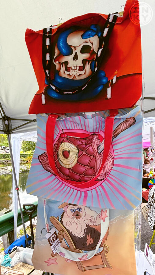 Side view of the booth layout at an outdoor market showing totebags.